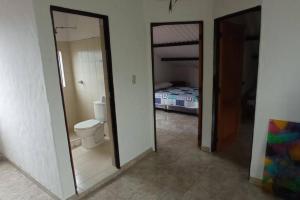 een badkamer met een toilet en een slaapkamer met een bed bij Finca la cristalina in Moniquirá