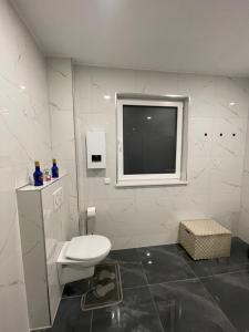a white bathroom with a toilet and a television at Pension Hammer in Mensfelden