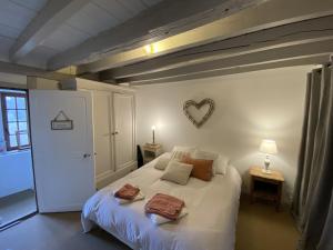 una camera da letto con un letto bianco con un cuore sul muro di La Courmonière a Courmont