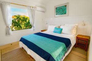 a bedroom with a large bed with a window at Pousada Maré in Búzios