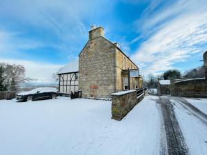 a building in the snow with a car parked in front at Shandwick House in Tain