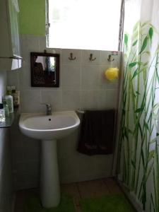 La salle de bains est pourvue d'un lavabo blanc et d'un miroir. dans l'établissement Maison type F3 Chez Jean Michel avec parking Chez Jean Michel, à Sainte-Rose