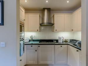 uma cozinha com armários brancos e um forno com placa de fogão em Stone Cottage em Shrewsbury