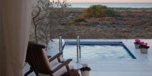 een patio met een zwembad en een stoel en bloemen bij Yamim Suites On The Beach in Shave Ẕiyyon