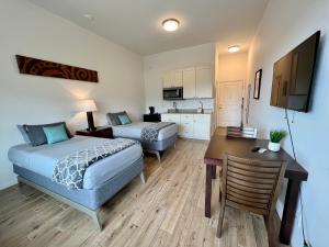 a bedroom with two beds and a desk and a kitchen at Unit 7 Maui Ohana Modern Studio in Wailuku