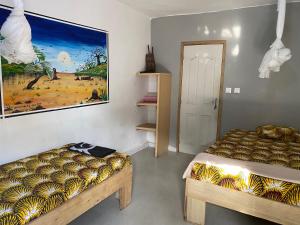 Cette chambre comprend deux lits et un tableau mural. dans l'établissement La kora, à Toubakouta