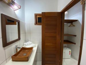 y baño con lavabo de madera y espejo. en Hospedaria Zukka Trancoso, en Trancoso