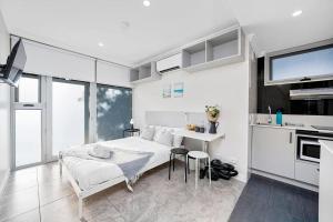 a white bedroom with a bed and a kitchen at Cozy Studio located in Crows Nest in Sydney