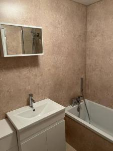 a bathroom with a sink and a mirror and a tub at 5 minutes to Glasgow airport in Paisley