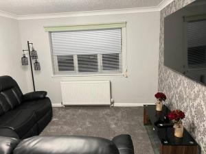 a living room with a leather couch and a window at 5 minutes to Glasgow airport in Paisley