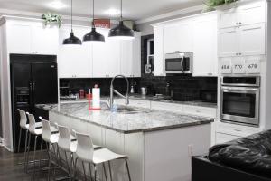 una cucina con mobili bianchi e un bancone con sgabelli di Adair Park Bungalow ad Atlanta