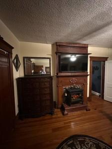 a living room with a television and a dresser with a fireplace at The Queen's Gambit ( A Luxury 2nd Floor Apt in Downtown Staunton) in Staunton