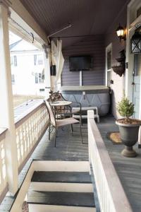 a porch with a table and chairs and a television at The Queen's Gambit ( A Luxury 2nd Floor Apt in Downtown Staunton) in Staunton
