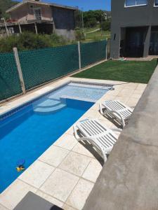 una piscina con 2 sillas de jardín junto a ella en Casa de montaña en San Roque