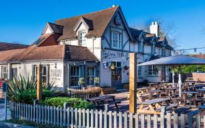 a restaurant with tables and an umbrella in front of a building at Scarlet Oaks, easy walk from Hospital in Frimley