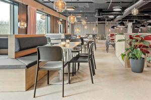 un restaurante con mesas, sillas y plantas en Aiden by Best Western Herning, en Herning