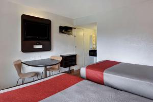 a hotel room with a bed and a table and a tv at Motel 6 Dania Beach in Dania Beach