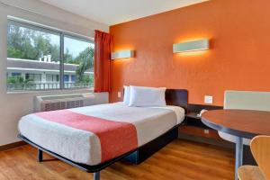 a room with a bed and a table and a window at Motel 6 Dania Beach in Dania Beach