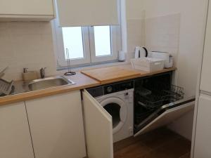 a kitchen with a washing machine and a sink at Casa da Praia da Poça - Apartamento Íris in Estoril +4 photos