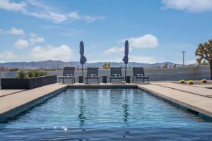 - une piscine avec des chaises longues devant un bâtiment dans l'établissement Mountain View Paradise -POOL & SPA, à Yucca Valley