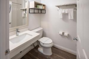 La salle de bains blanche est pourvue d'un lavabo et de toilettes. dans l'établissement Ramada by Wyndham Redondo Beach, à Redondo Beach