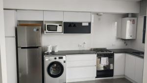 eine Küche mit einem Kühlschrank, einer Waschmaschine und einer Mikrowelle in der Unterkunft Moderno 2 amb con Cochera in Mar del Plata