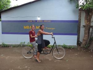 dos personas montando una bicicleta delante de un edificio en Mbah Mek Trawangan Homestay, en Gili Trawangan