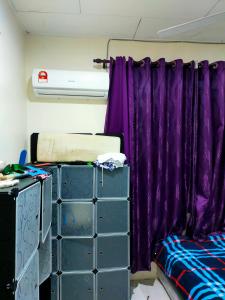 Habitación con cortinas moradas junto a la cama en Alor Setar Homestay en Kuala Kedah