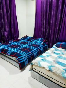 1 dormitorio con 2 camas y cortinas moradas en Alor Setar Homestay en Kuala Kedah