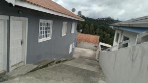 ein graues Haus mit einer weißen Tür und einem Zaun in der Unterkunft Cantinho aconchegante in Campos do Jordão
