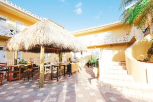 een restaurant met tafels en stoelen en een rieten parasol bij Hollywood Beach Hotels in Hollywood