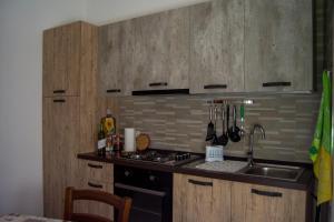 a kitchen with wooden cabinets and a stove and a sink at MADACHI APPARTAMENTI in Trapani