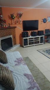 ein Wohnzimmer mit einem TV und einem Kamin in der Unterkunft Cantinho aconchegante in Campos do Jordão