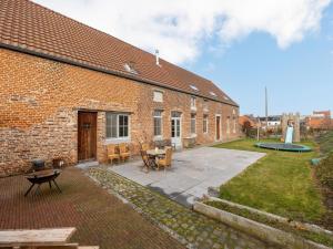 a brick building with a patio with a table and chairs at Magnificent square farm in the beautiful blossom region in Sint-Truiden