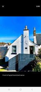 una casa blanca con una valla delante en The Lodge Dunrowan en Kyle of Lochalsh