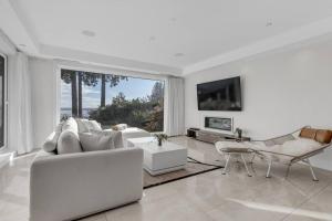 un soggiorno bianco con divano e TV di Modern Home with Breathtaking Ocean & City Views a West Vancouver