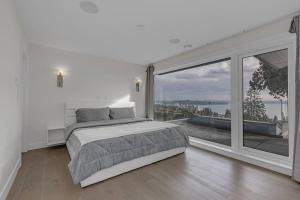 una camera bianca con un letto e una grande finestra di Modern Home with Breathtaking Ocean & City Views a West Vancouver