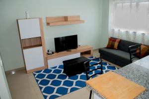 uma sala de estar com um sofá e uma televisão em Comfortable and Cozy Apartments em Praia