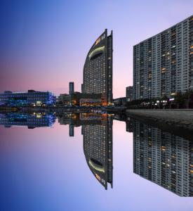 un reflet d'un bâtiment dans une masse d'eau dans l'établissement Bayshore Hotel Dalian, à Dalian