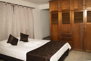 a bedroom with a bed and a wooden cabinet at villa de las palmas in Palmira