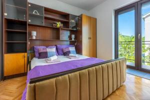 a bedroom with a large bed with purple sheets at Apartment Klaudia in Dramalj