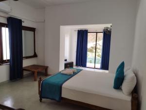 a bedroom with a bed with blue curtains and a window at HangarankandaBungalow Deniyaya in Deniyaya