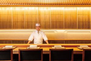 een chef-kok die achter een tafel in een restaurant staat bij Imperial Hotel Tokyo in Tokyo