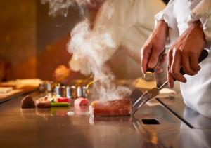 東京的住宿－東京帝國酒店，厨师用刀在柜台上烹饪食物