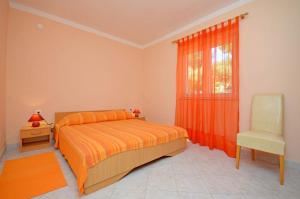 a bedroom with a bed and a chair and a window at Apartments Vesna in Lastovo
