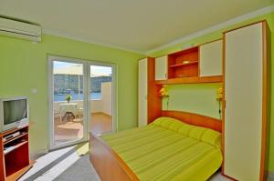 a bedroom with a bed and a tv and a balcony at Apartments Vesna in Lastovo