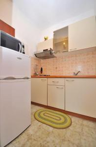 a kitchen with a white refrigerator and a sink at Apartments Slavica in Ubli
