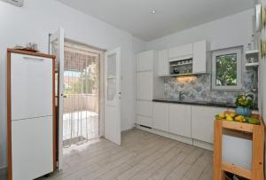 a kitchen with white cabinets and a window and a door at Apartments Nikica in Seget Vranjica