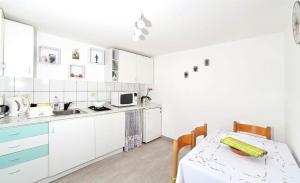 a kitchen with white cabinets and a table and a sink at Apartment Sanja in Martina