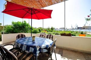- une table avec un parasol rouge sur la terrasse dans l'établissement House Ivica, à Trogir